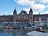 Historic Amsterdam 2025 train station by the waterfront canal.