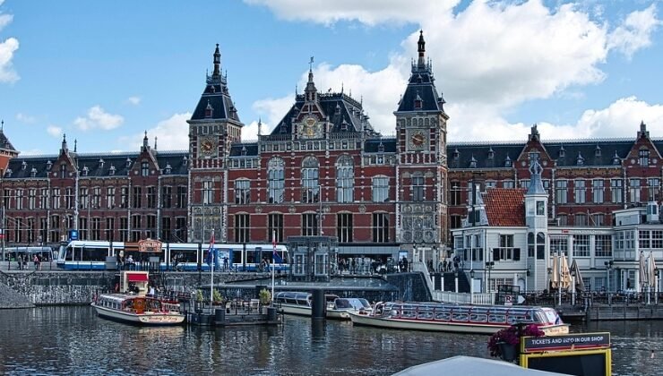 Historic Amsterdam 2025 train station by the waterfront canal.