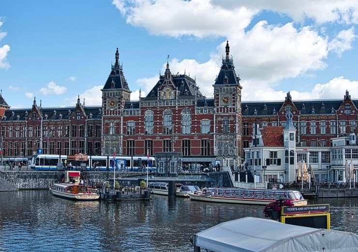 Historic Amsterdam 2025 train station by the waterfront canal.