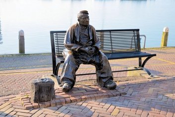 Sculpture of a man sitting near water in the Volendam Harbor