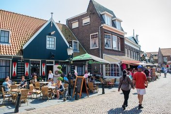 People enjoying outdoor cafes on a sunny street in Volendam